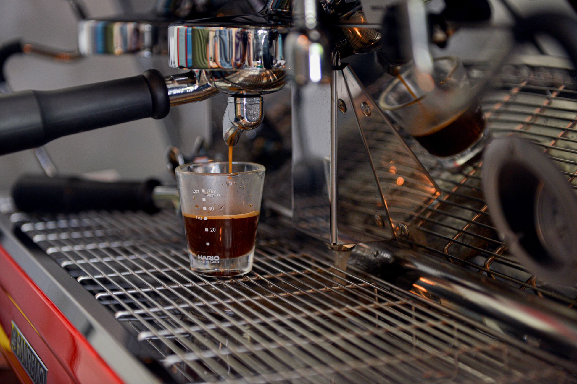 Close-up of espresso being poured into a glass from a coffee machine in a cafe setting.