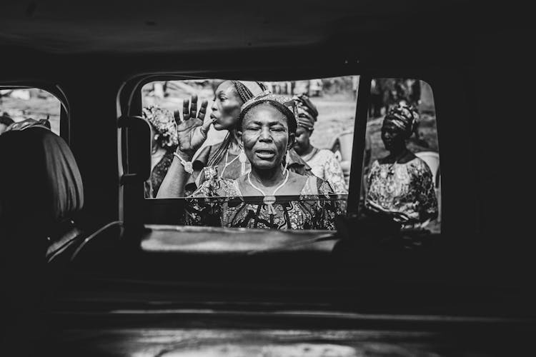 Woman Waving Behind Car Window Among Women