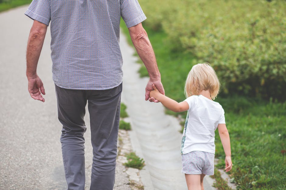 Man and Child Walking Near Bushes during Daytime