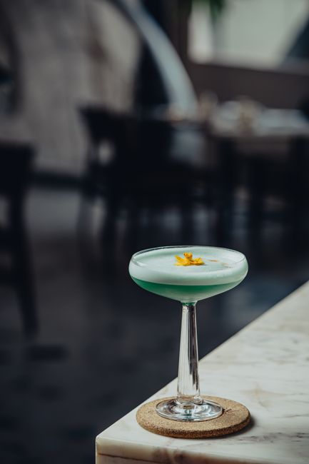 Stylish cocktail with garnish on a marble table in a dimly lit indoor setting.