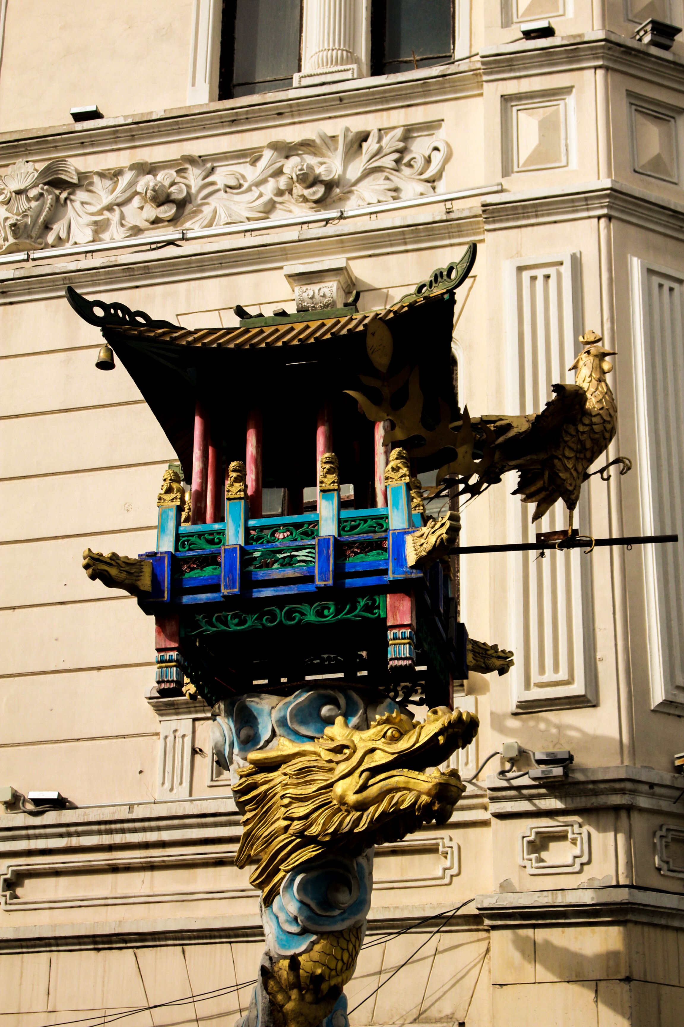 Traditional Asian ornamental structure with dragon and phoenix located outside a building.