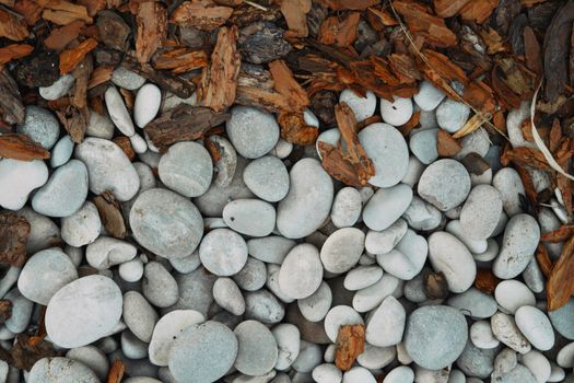 Top view of smooth gray stones and brown bark chips, perfect for landscaping designs.