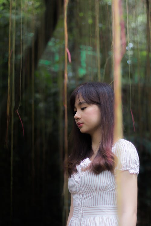 Young Woman in a White Dress Standing in a Garden 