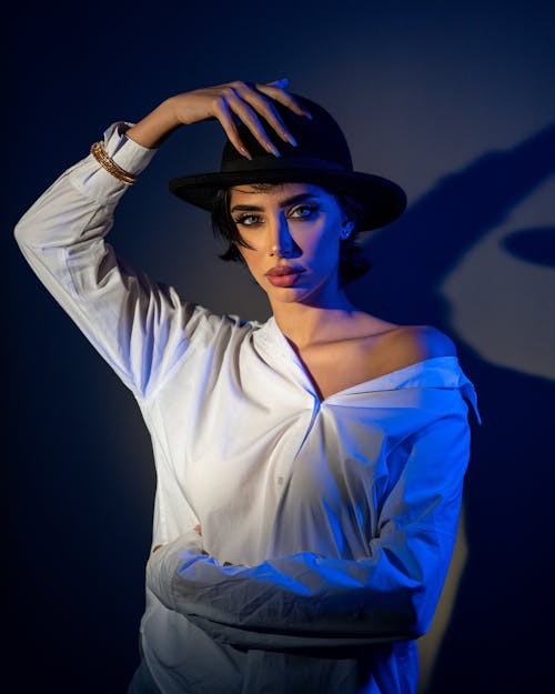 Beautiful Woman in White Shirt with Right Hand on Her Hat