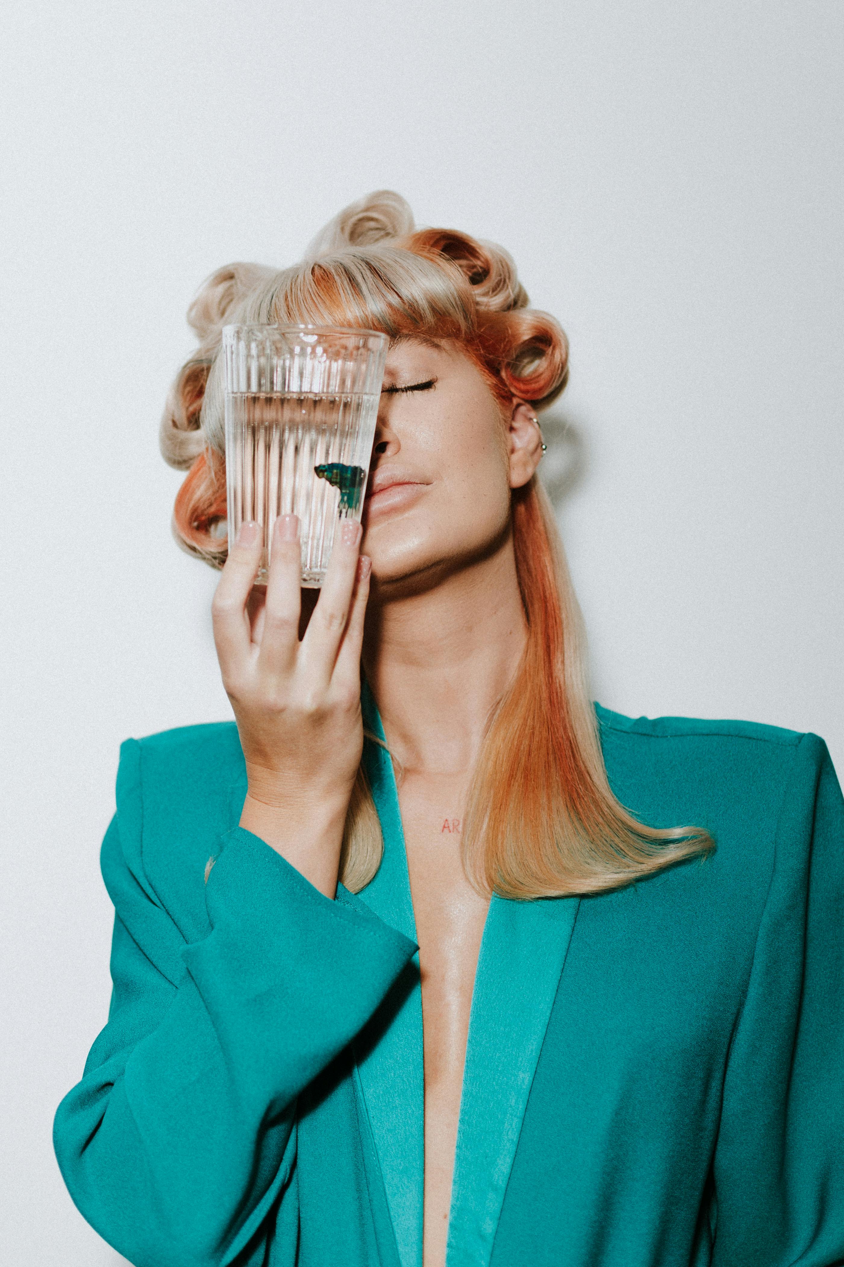 Vibrant fashion portrait featuring a woman with retro hairstyle holding a glass with butterfly art.