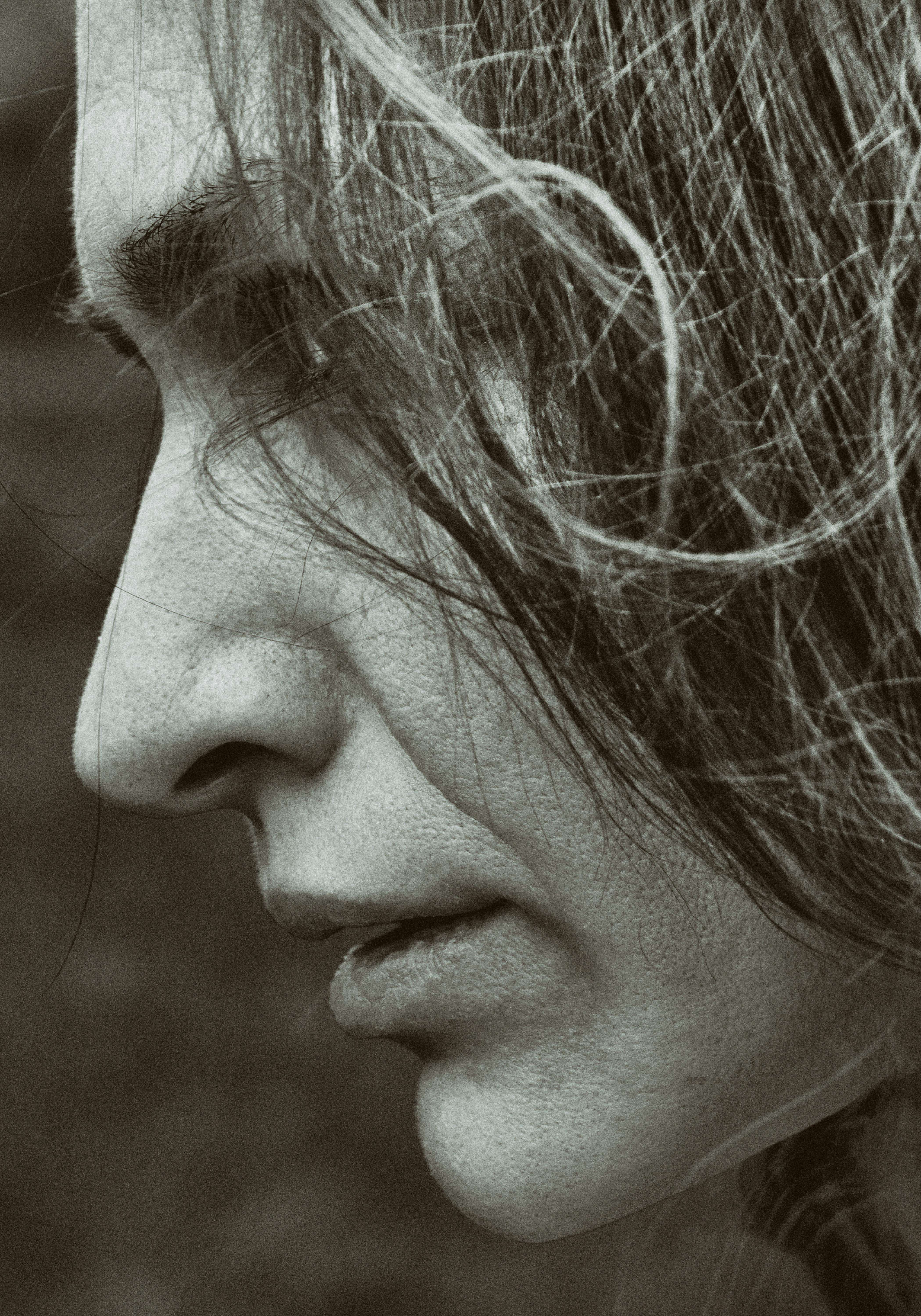 Close-up black and white profile of a woman with artistic focus on texture and emotion.