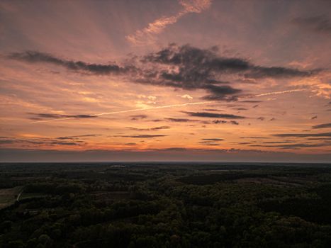 Stunning drone shot capturing a vibrant sunset over a lush Virginia forest.