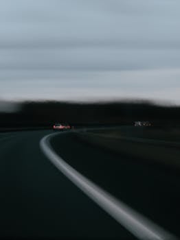 Moody abstract shot of a highway curve with blurred cars at dusk.