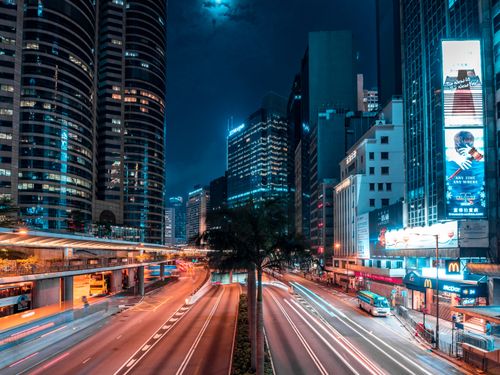 Free Illuminated urban scene with skyscrapers and busy streets captured at night, featuring dynamic light trails. Stock Photo