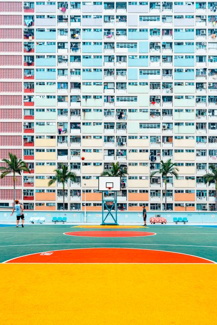 A vibrant basketball court in front of a colorful high-rise building, showcasing urban life.