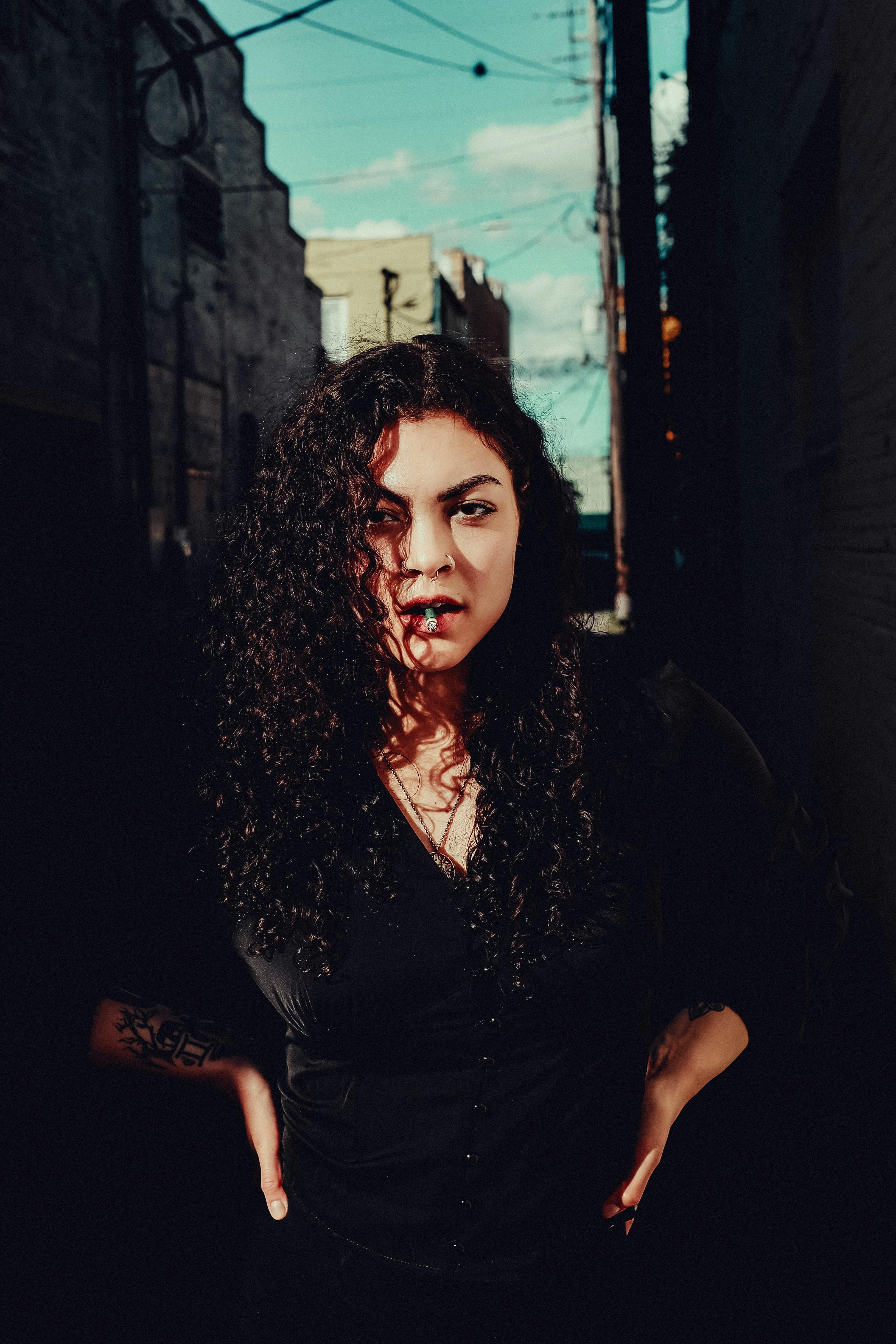 a woman with curly hair standing in an alley