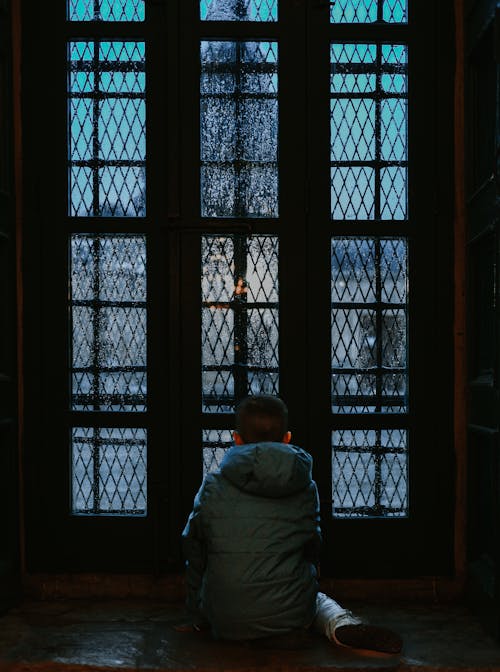 A child sitting in front of a window looking out