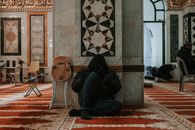 Interior of a mosque with ornate designs and a person photographing.