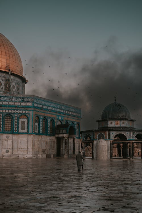 A man walking in front of the dome of the rock