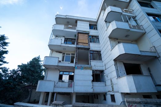 Low angle shot of a damaged residential building exterior with visible balconies and wear.