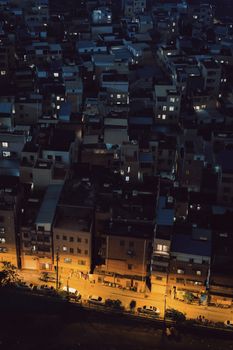 Aerial shot of a densely-packed urban residential area at night, with illuminated streets.