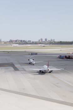 Airplanes taxiing on the tarmac at JFK Airport, New York City on a clear day.