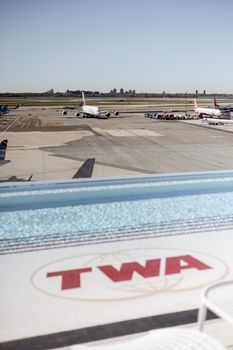 Airplanes parked on the tarmac at New York City's airport with TWA branding in view.