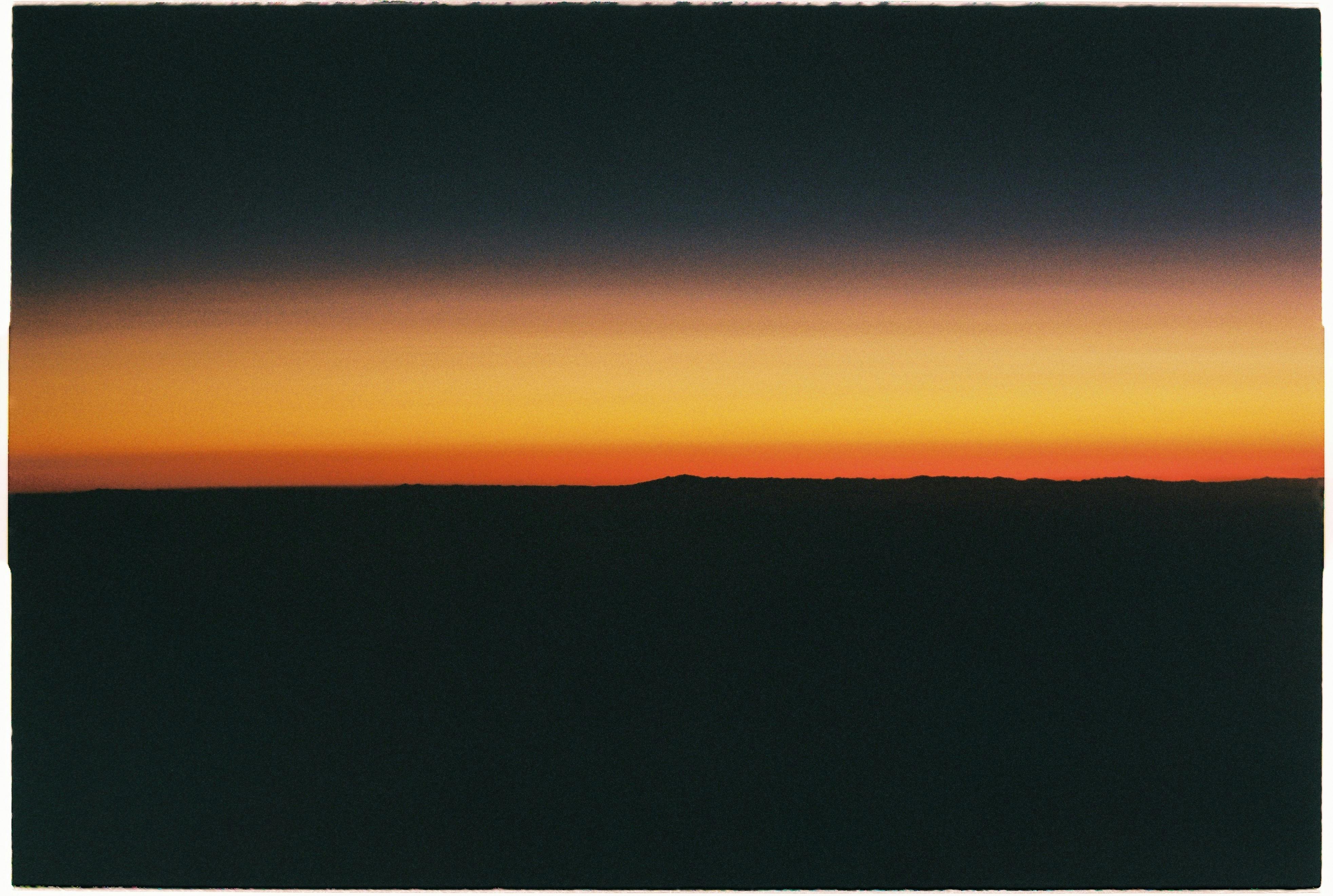 A stunning sunset silhouette with vibrant yellow sky and dark horizon.