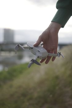 Close-up of a hand holding a compact drone outdoors, showcasing technology.