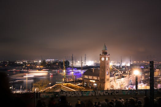 A dramatic night cityscape of the Landungsbrücken harbor in Hamburg, Germany, with vibrant city lights.