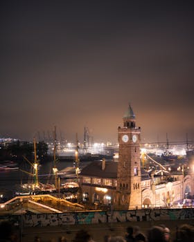 Moody night view of the illuminated Hamburg Landungsbrücken, featuring the historic tower and bustling harbor.