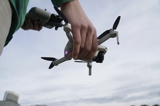 Close-up of a person holding a drone, ready for launch in an outdoor setting.