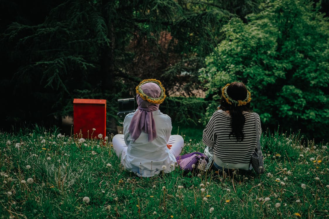 Women in Flowers Wreaths Sitting on Meadow