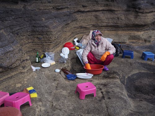 Elderly Woman Crouching on Rock Shelf