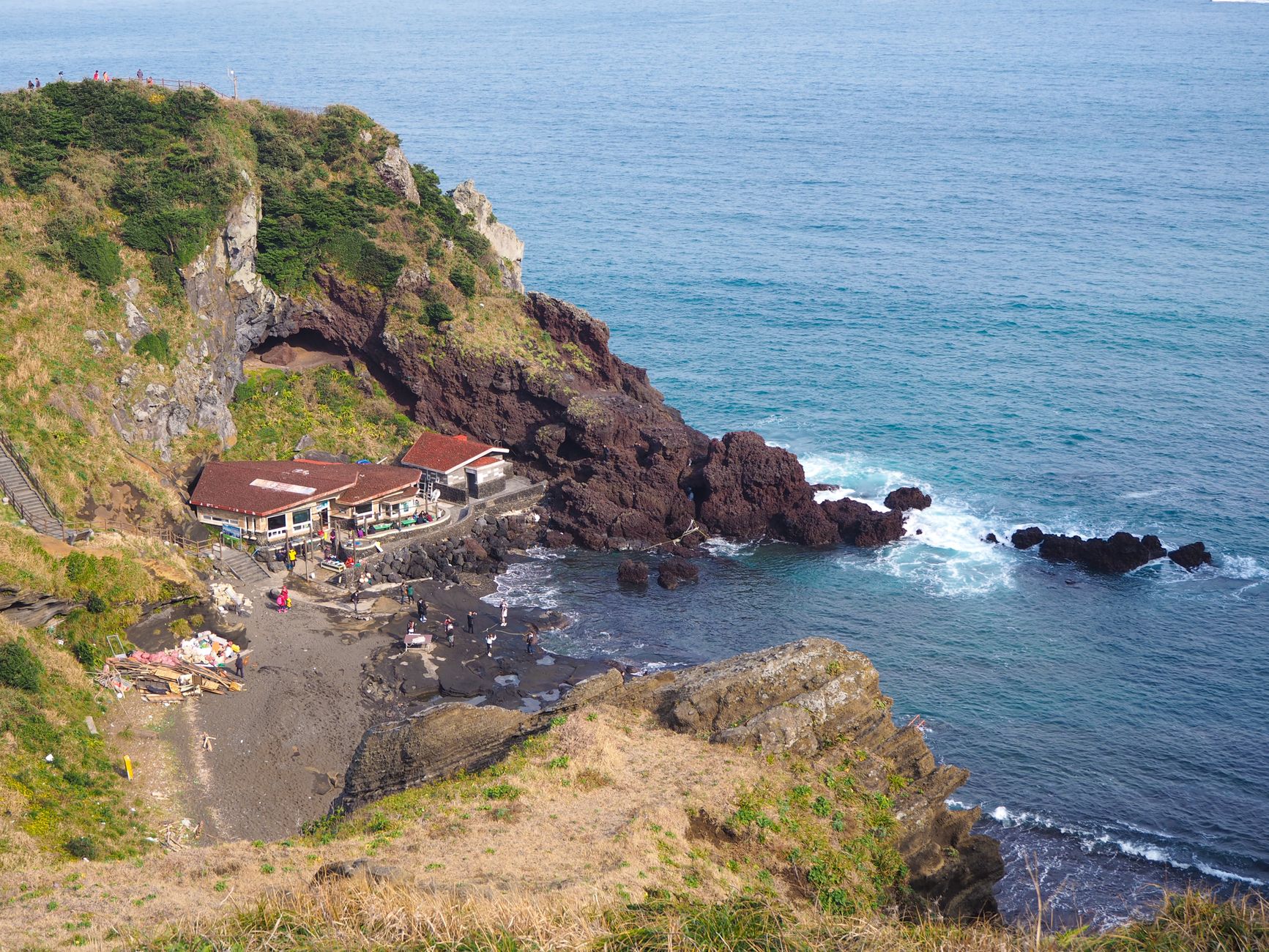 Aerial shot capturing a scenic coastal cliff with buildings near the sea.