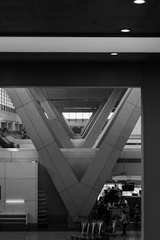 Black and white photo showcasing the symmetry and modern architecture of an airport terminal in Pasay, Philippines.
