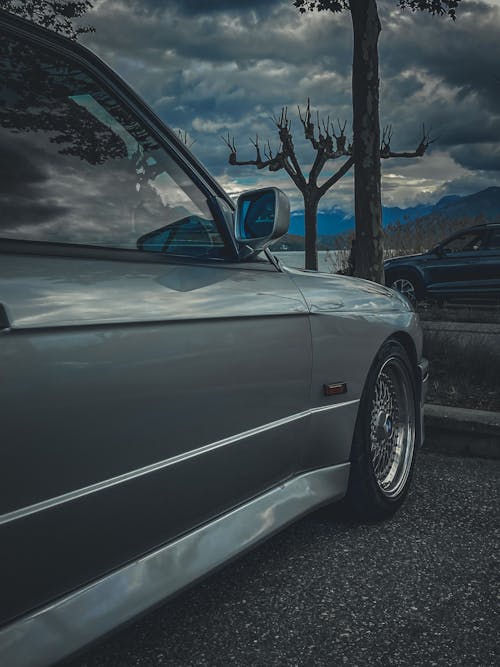 A Gray BMW E30 on a Parking Lot with Mountains in the Background 