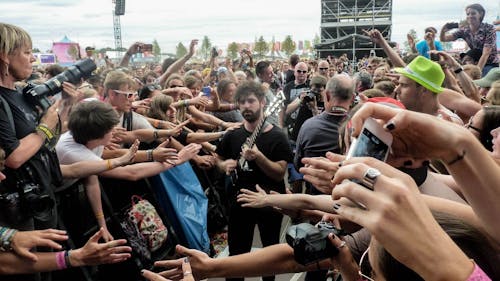 Free Man in Black Crew Neck T Shirt and Pants Playing Guitar Surrounded by Crowd Stock Photo