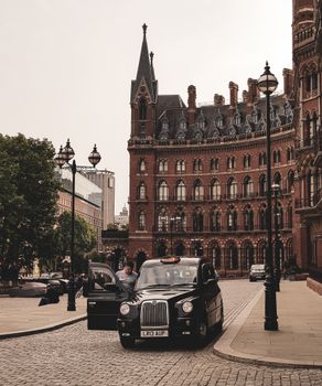 A traditional black London taxi outside the iconic St Pancras Renaissance Hotel.