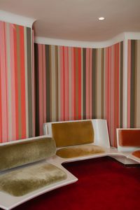 Vintage-inspired lounge with colorful striped walls and plush seating at TWA Hotel, NYC.