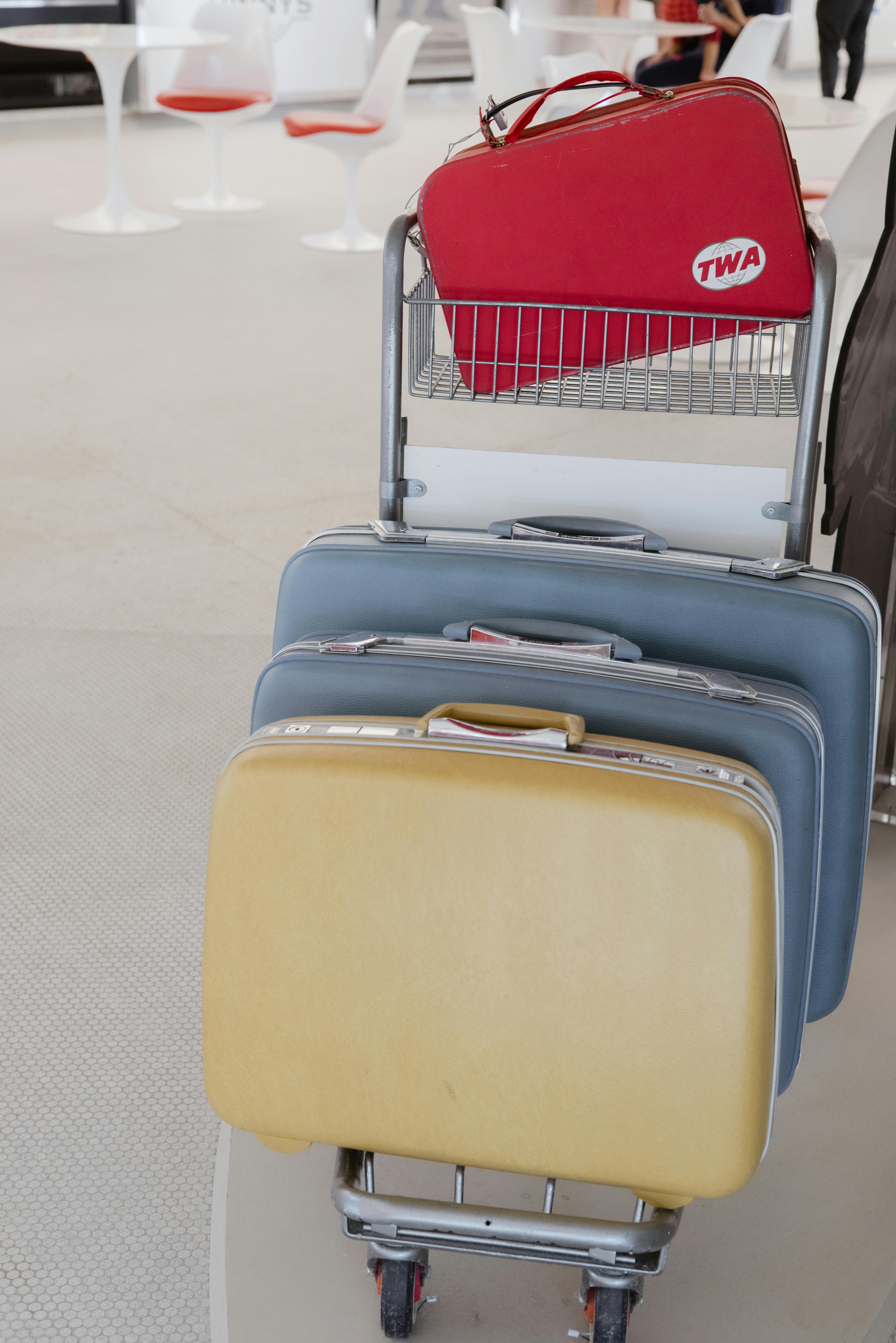 Retro 1960s TWA luggage cart with colorful suitcases at JFK Airport terminal.