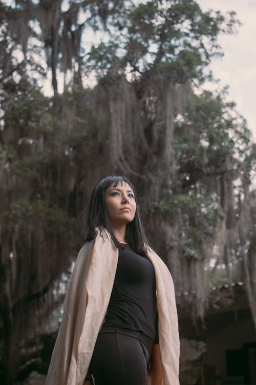 Young Woman in a Coat Standing on the Background of a Tree