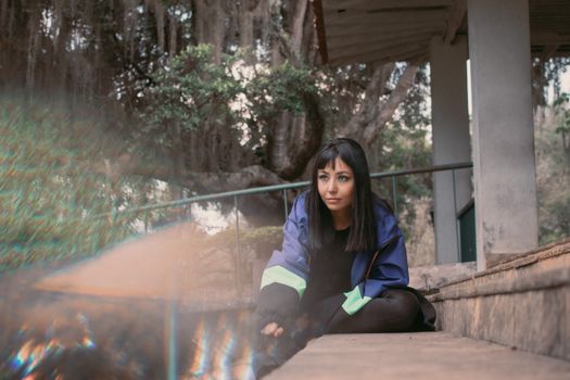 A woman in casual attire sitting on outdoor steps surrounded by nature.