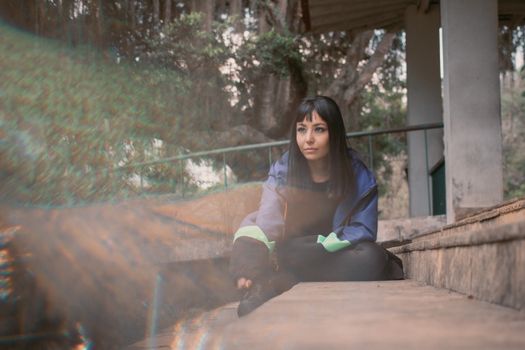 Young woman with bangs sitting on steps during fall, enjoying relaxation outdoors.