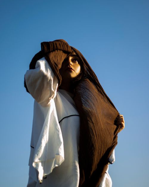 Free Young woman stands with a brown headscarf in Tabriz, Iran, looking towards the sky. Stock Photo