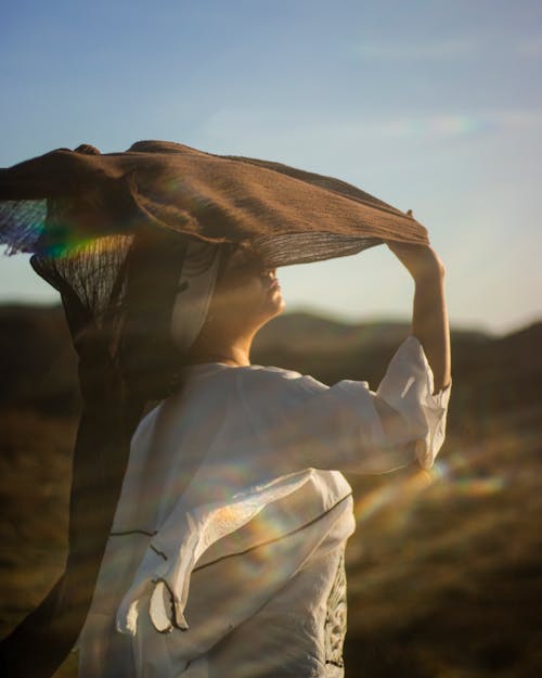 Young Woman Standing Outside in Sunlight and Holding a Brown Shawl 