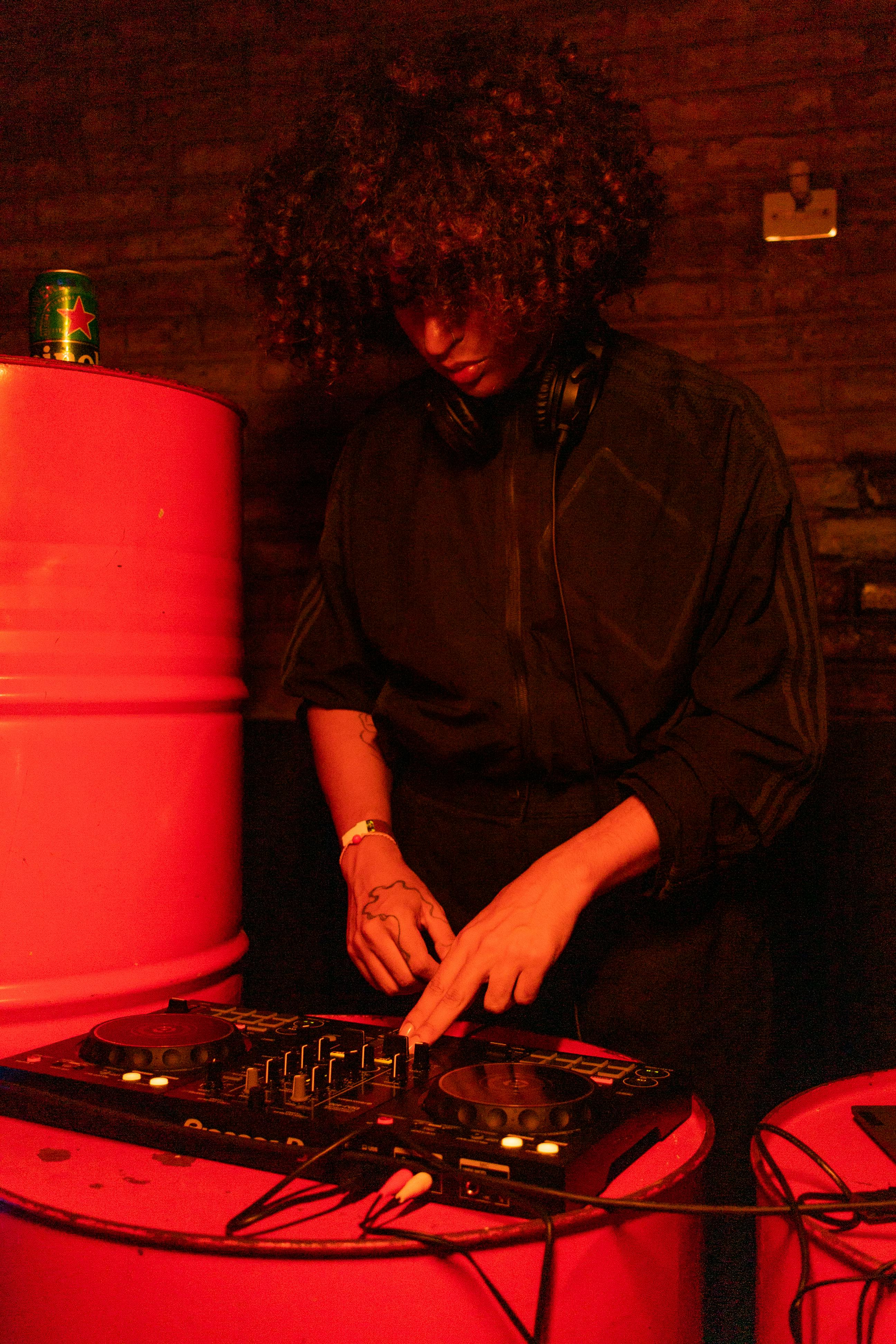 DJ playing music in nightclub with red lighting. Energetic and modern vibes.