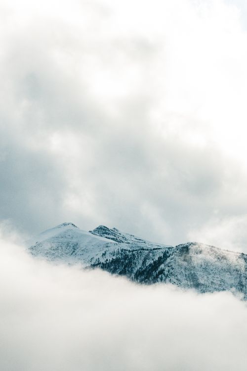 Free A serene view of snow-capped mountain peaks shrouded in clouds in Banff, Alberta, Canada. Stock Photo