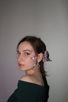 Artistic portrait of a young woman with delicate floral makeup and green dress.