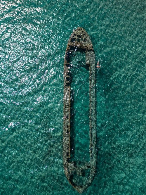 Free Top view of a sunken ship in clear turquoise waters near Gemikonağı, creating a stunning underwater scene. Stock Photo