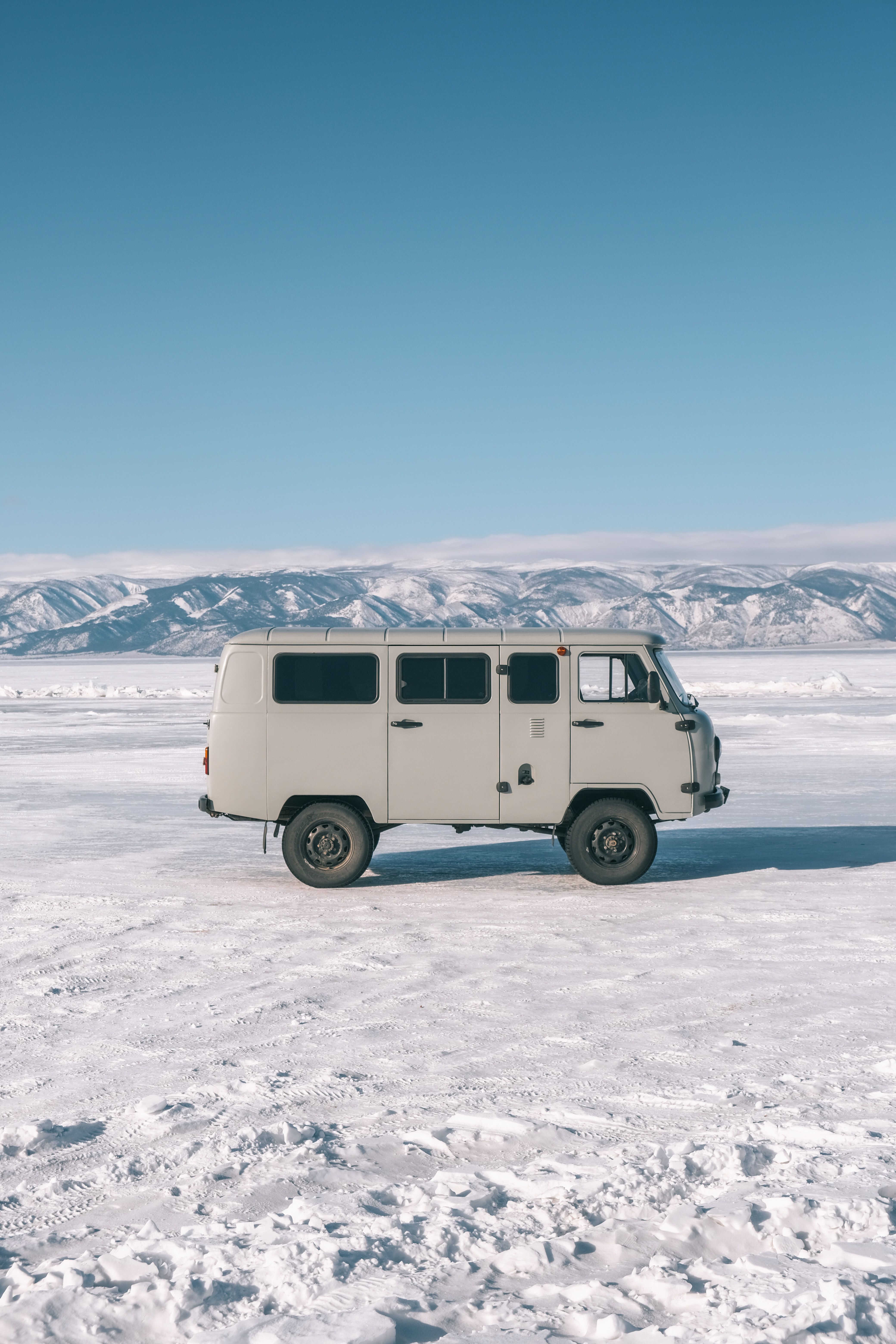 Vintage van on a vast snowy landscape with mountains in Baykalsk, Russia.