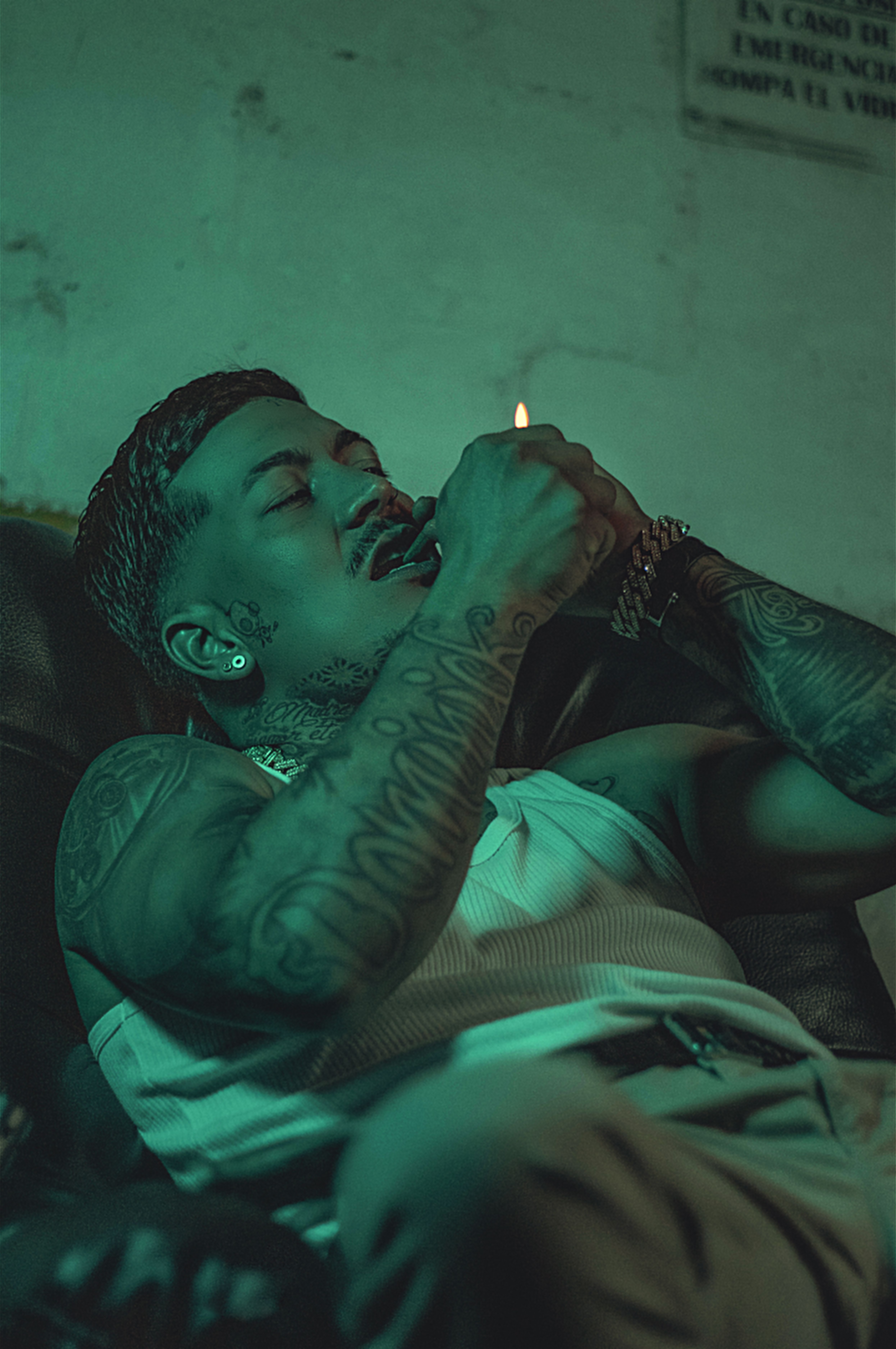 Tattooed man with short hair lighting a cigarette indoors in Medellín, Colombia.