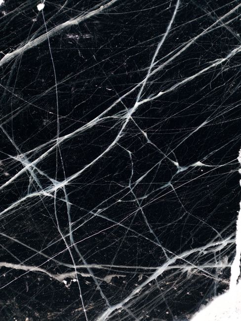 A close-up view of intricate black ice with white cracks, showcasing nature's artistry.