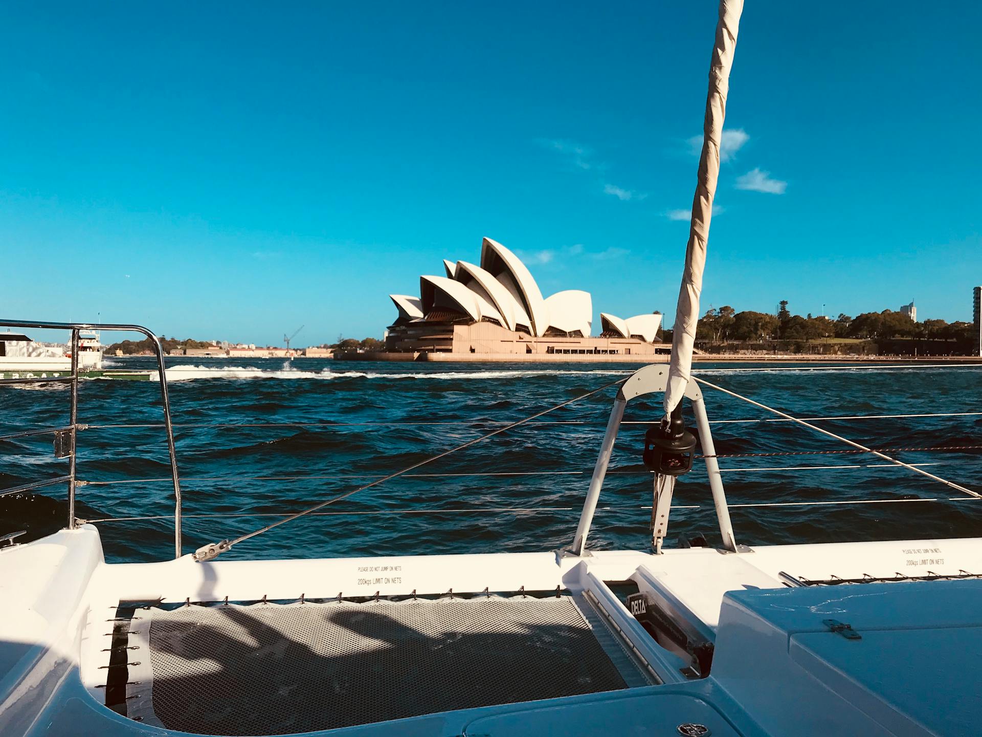 Experience a stunning view of the Sydney Opera House from a yacht on a sunny day.