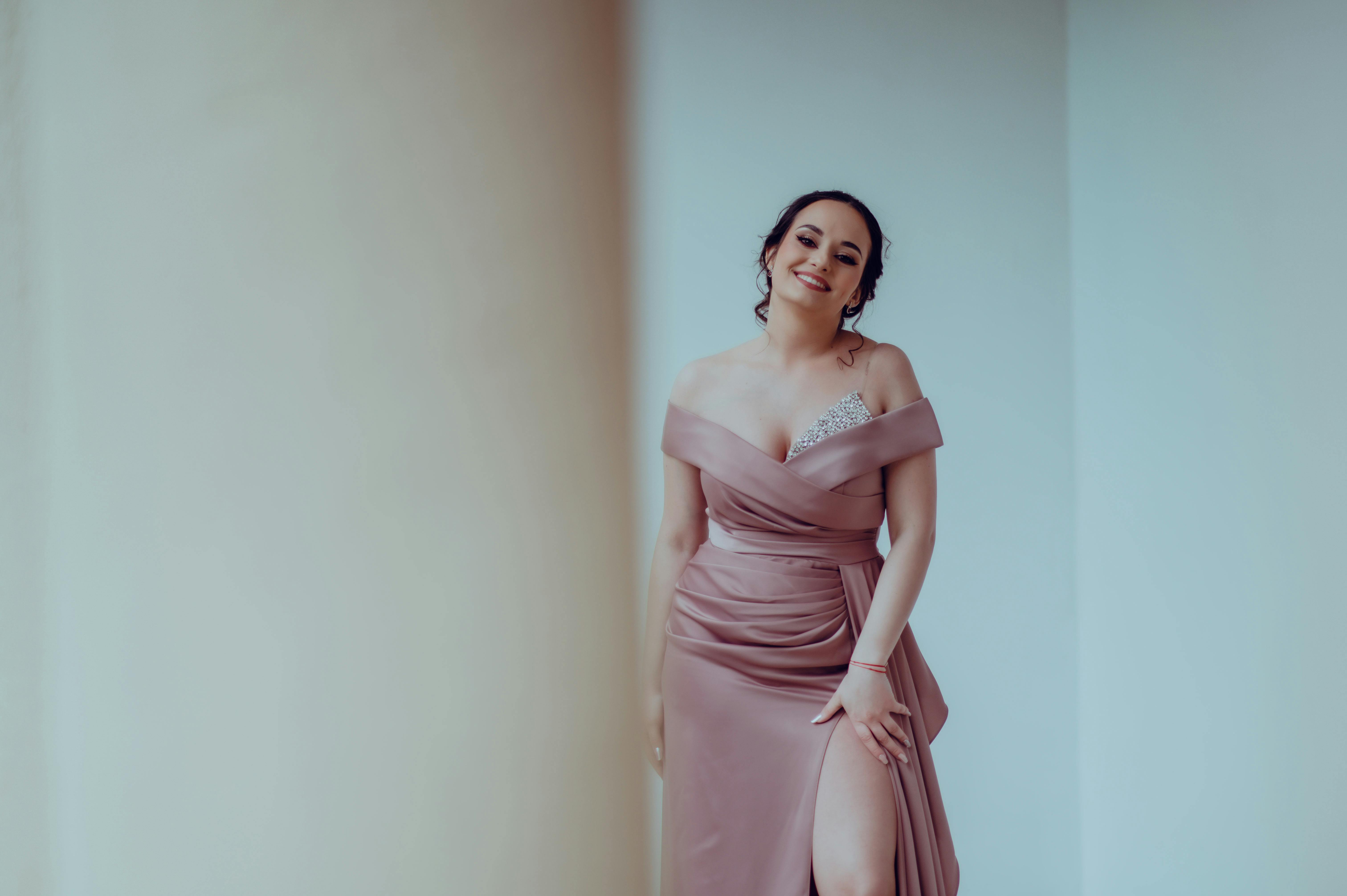 Elegant woman in a glamorous dress posing indoors with a joyful smile.